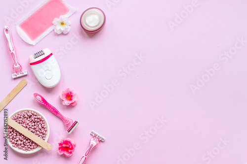 Set of epilation means - epilator with wax strips, razor and flowers. Top view