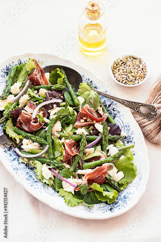 Delicious prosciutto, mozzarella and asparagus salad on table