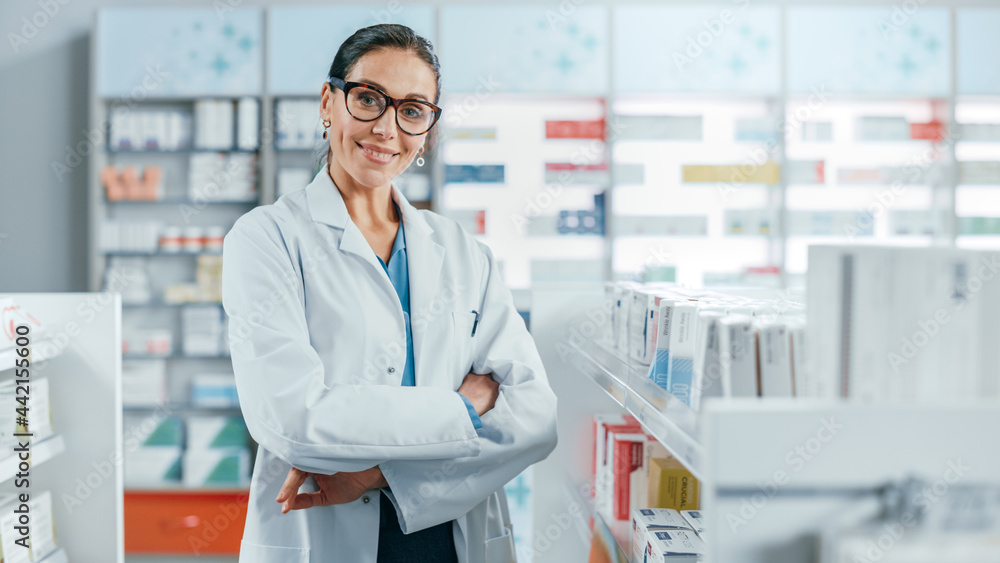 Pharmacy: Portrait of Beautiful Professional Caucasian Female Pharmacist Wearing Glasses, Crosses Arms and Looks at Camera Smiling Charmingly. Drugstore Store with Shelves Health Care Products