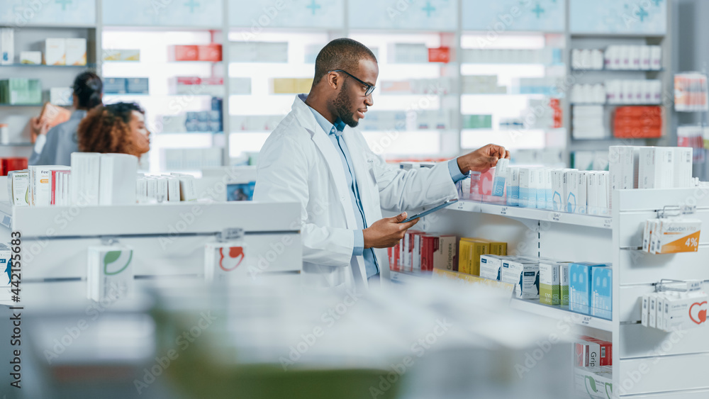 Pharmacy: Portrait of Professional Black Pharmacist Uses Digital Tablet Computer, Checks Inventory of Medicine, Drugs, Vitamins, Health Care Products. Druggist in Drugstore Store.