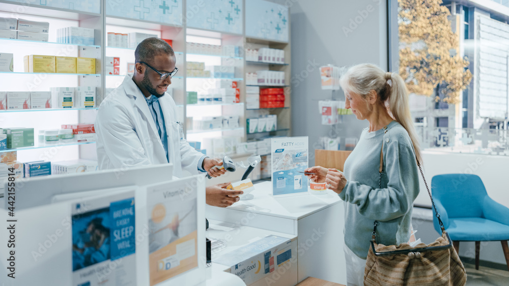 Pharmacy Drugstore Checkout Counter: Professional Black Male Pharmacist Provides Service, Sells Medicine to Diverse Group of Multi-Ethnic Customers, they Pay Using Contactless Payment Credit Cards