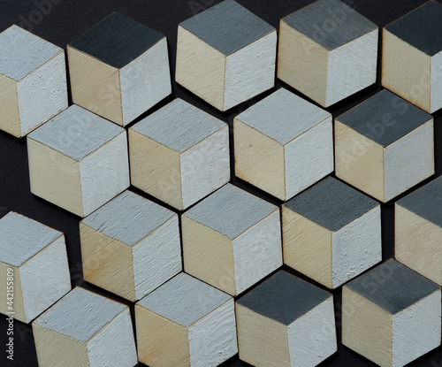 3d wooden cubes (hexagons) hand painted in white and various shades of gray acrylic paint, loosely arranged on a medium gray paper background, and photographed from above in a flat lay style with ambi