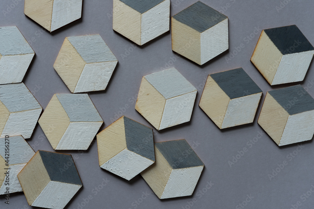 3d wooden cubes (hexagons) hand painted in white and various shades of gray acrylic paint, loosely arranged on a medium gray paper background, and photographed from above in a flat lay style with ambi 3d wooden cubes (hexagons) hand painted in white and various shades of gray acrylic paint, loosely arranged on a medium gray paper background, and photographed from above in a flat lay style with ambi