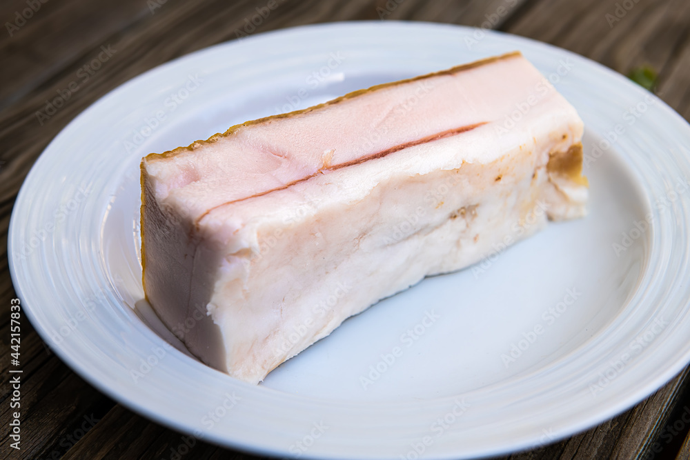 Closeup of traditional salted pork belly fat food for making sandwiches from slices of the lard as traditional Russian cuisine on plate Closeup of traditional salted pork belly fat food for making sandwiches from slices of the lard as traditional Russian cuisine on plate