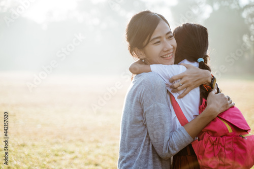 asian mother embrace and hug her daughter wearing uniform when going to school in the morning