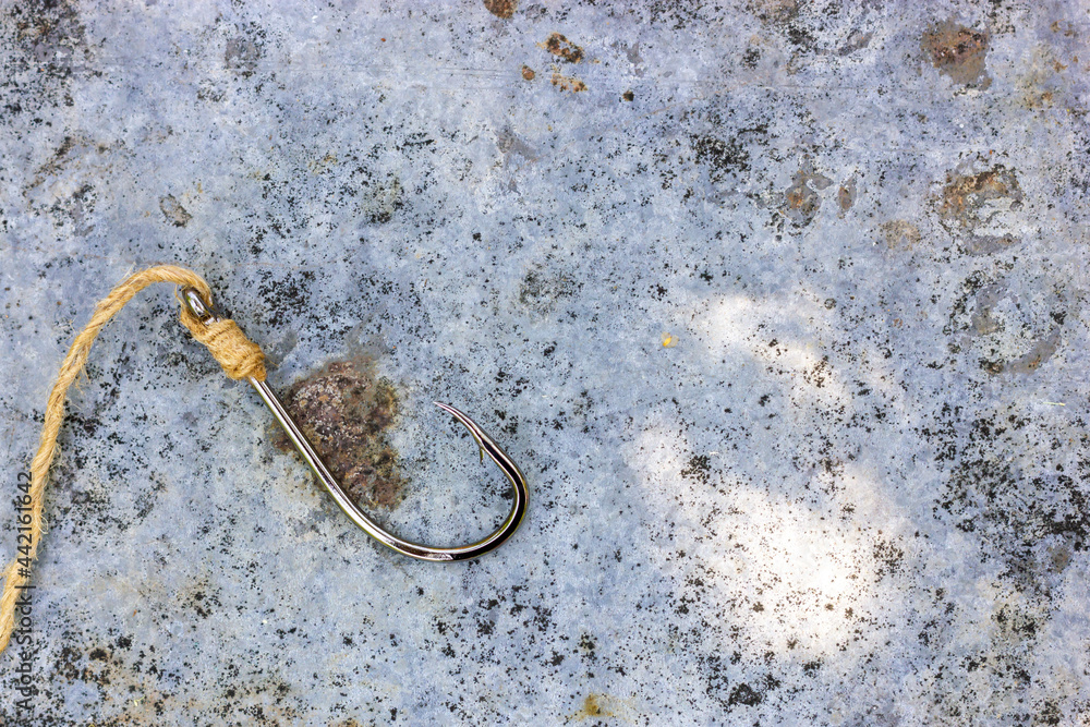 A large fishing hook on a rusty metal surface. Fishing hook. An empty hook.