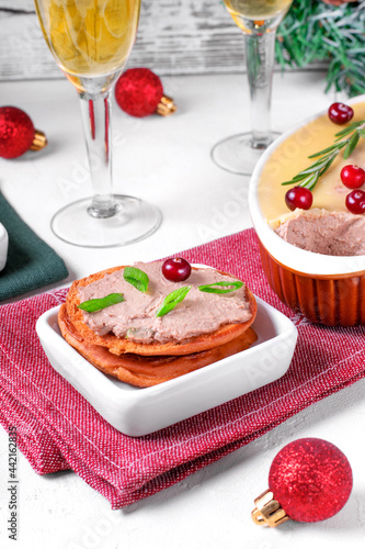 Chicken liver pate with butter served on toasted bread on the white table prepared for festive dinner. Christmas cold appetizer