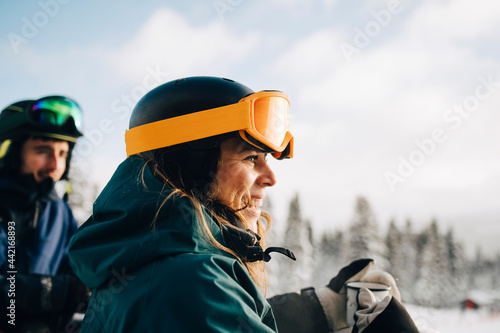 Leende kvinna med skidutrustning står med vänner photo