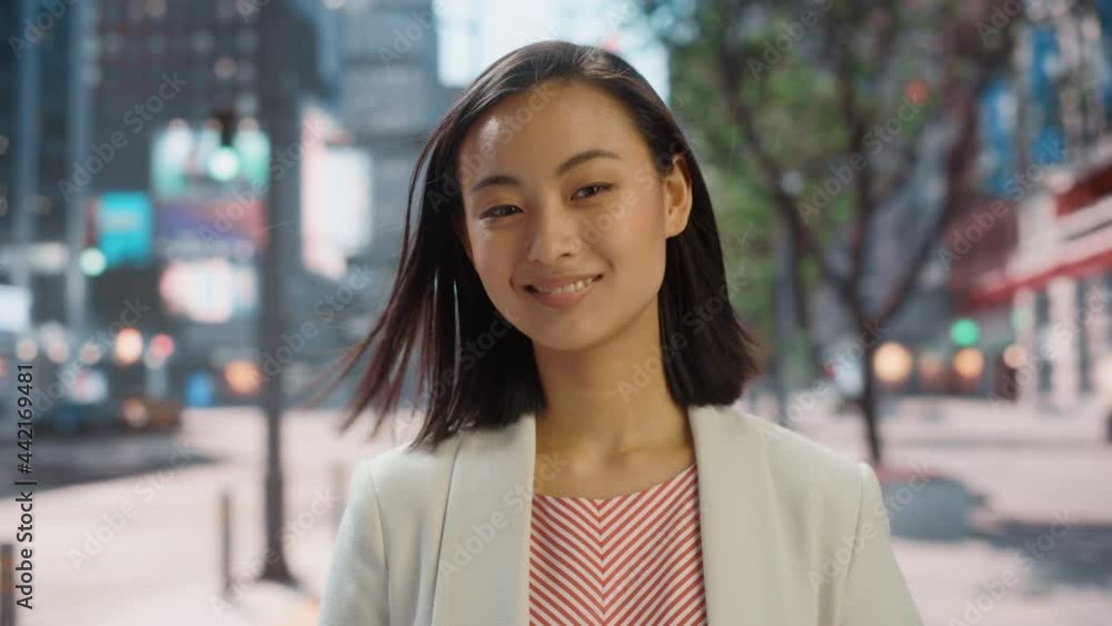 Portrait of Beautiful Japanese Female Wearing Smart Casual Clothes Posing on the Street. Successful Female in Big City Living the Urban Lifestyle. Background with Office Buildings and Billboards. Portrait of Beautiful Japanese Female Wearing Smart Casual Clothes Posing on the Street. Successful Female in Big City Living the Urban Lifestyle. Background with Office Buildings and Billboards.