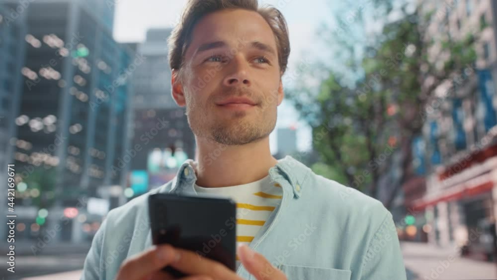 Portrait of a Handsome Young Man Wearing Casual Clothes and Using Smartphone on the Urban Street. Smiling Male in Big City Connecting with People Online, Messaging and Browsing Internet. Portrait of a Handsome Young Man Wearing Casual Clothes and Using Smartphone on the Urban Street. Smiling Male in Big City Connecting with People Online, Messaging and Browsing Internet.