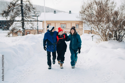 Tre glada vänner går tillsammans i stad under vinterdag photo