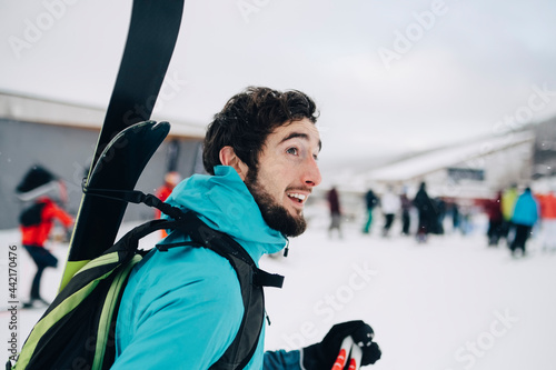 Man bär skidor på ryggen i skidbacke photo