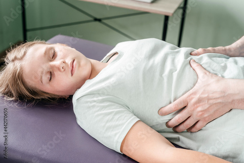 Osteopath practitioner releasing the diaphragm of a female patient, rib cage release massage, breathing muscle relaxation photo