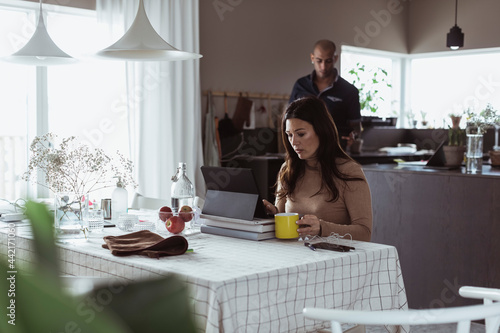 Koncentrerad entreprenör arbetar vid matbord hemma photo