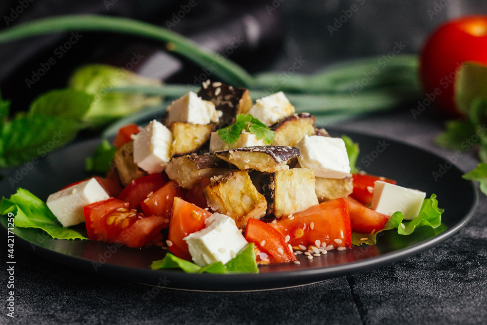 Salad with eggplants, tomatoes and feta cheese. Delicious salad on a plate Salad with eggplants, tomatoes and feta cheese. Delicious salad on a plate