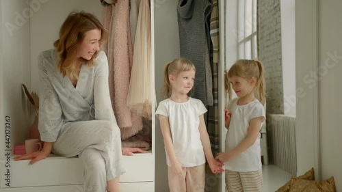 mom sits on the closet and looks at the camera with her daughters