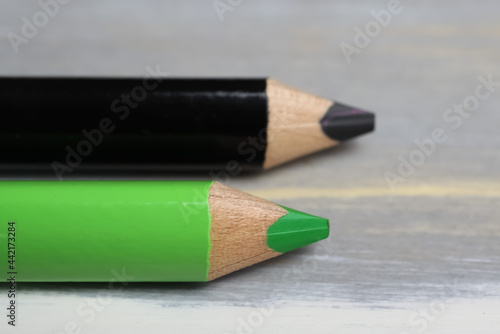 Closeup of isolated colorful black and green crayons on wood background - kiwi coalition concept photo