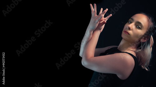 retrato de estudio sobre fondo negro de chica haciendo movimientos con las manos photo