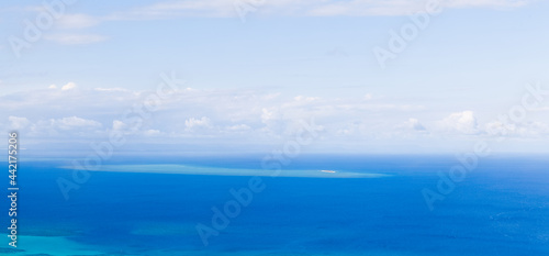A huge panorama on the horizon between the blue sea and the blue sky. The ocean floor is translucent and the shallows are visible. Turquoise water with white shallows. Blue sky. Sunny tropical day. 