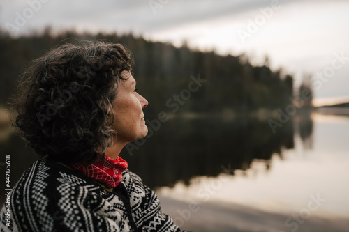 Kvinnlig utforskare tittar ut över sjö i skog photo