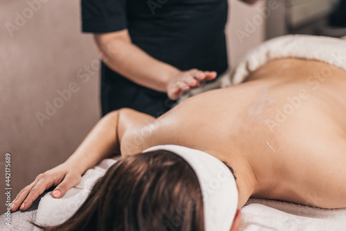 Relaxed woman on massage table in salon - back massage for wellness and pleasure
