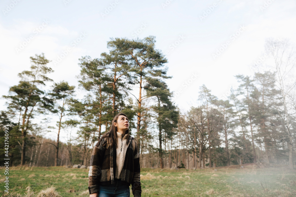 Kvinna tittar upp under vandring i skog Kvinna tittar upp under vandring i skog