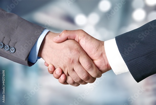 Businessmen reach out to each other to shake hands on a blur background.