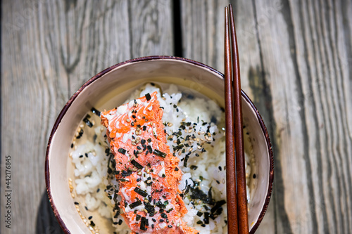 Closeup of traditional Japanese green tea meal dish in Asia called ochazuke with grilled salmon, rice sesame seed furikake and nori in bowl with chopsticks on wooden table photo