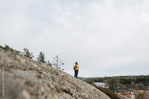 Kvinnlig utforskare står på höjd i skog photo