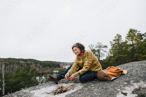 Kvinna förbereder eld på klippa i skog photo