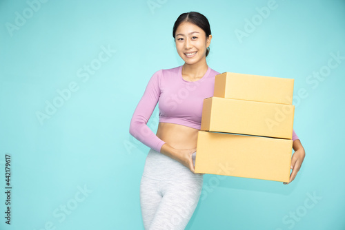 Happy Asian sporty woman holding package parcel box isolated on green background, Delivery and shopping express concept