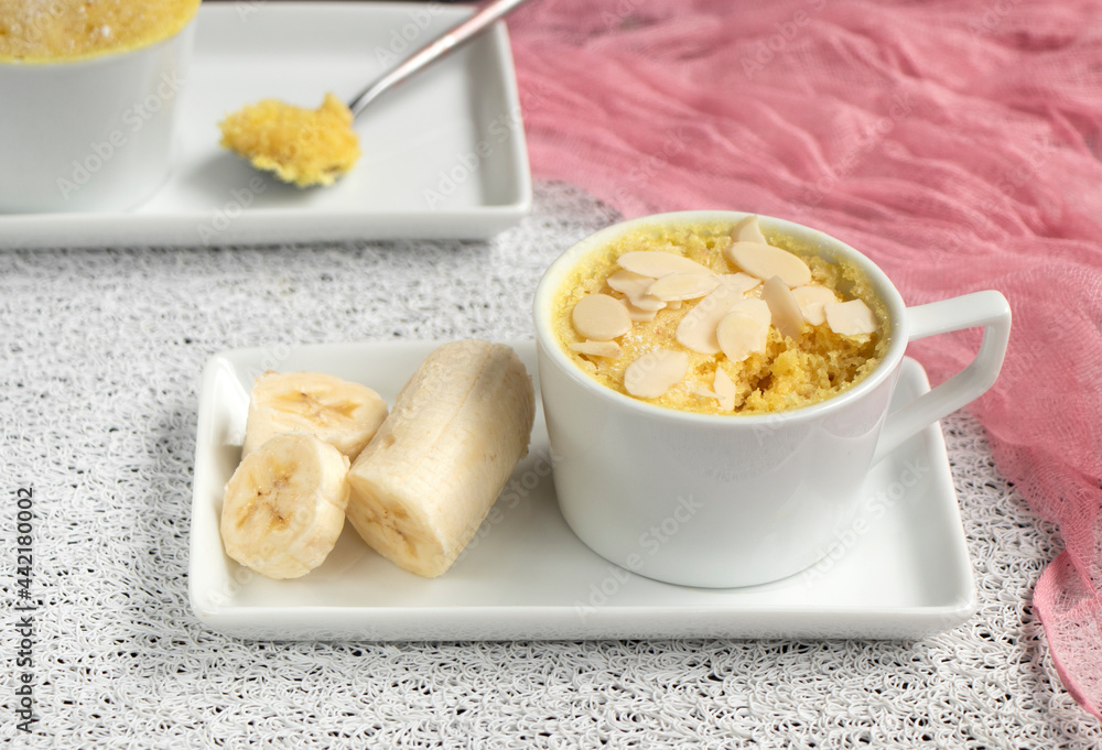 cupcake in a mug with banana pieces. Banana cupcake on a light background. The concept of a dessert in the microwave. bananas cake. High quality photo cupcake in a mug with banana pieces. Banana cupcake on a light background. The concept of a dessert in the microwave. bananas cake. High quality photo