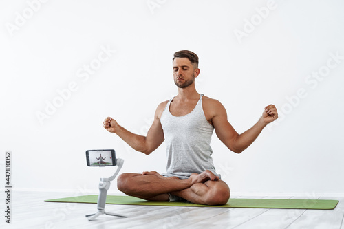 Fit Caucasian male recording a blog or streaming yoga workout. 
