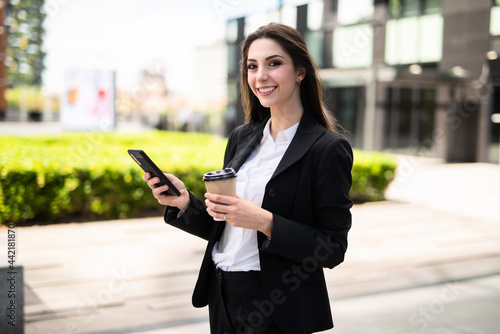 Businesswoman using her mobile phone while walking outdoor © Minerva Studio