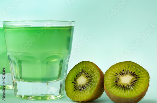 Sweet dessert, kiwi jelly in glass glasses and next to fresh kiwi cut in two halves on mint background