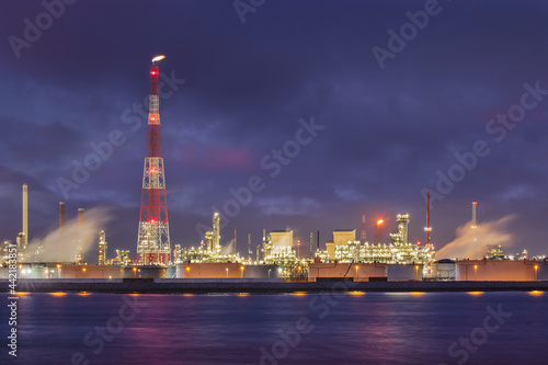 Night scene with illuminated petrochemical production plant on riverbank, Port of Antwerp