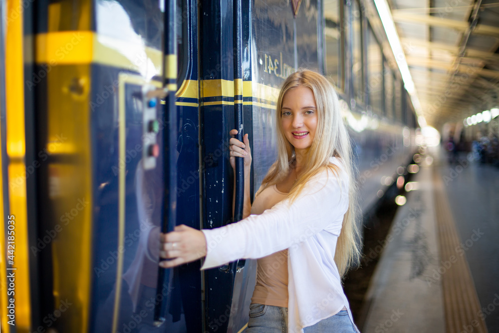 Portrait of young cheerful woman on train at station.