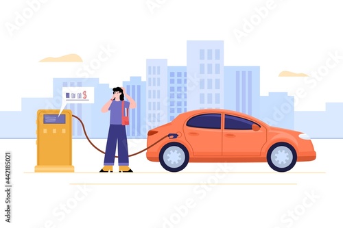Young woman talking mobile phone and filling up fuel into car at gas station.