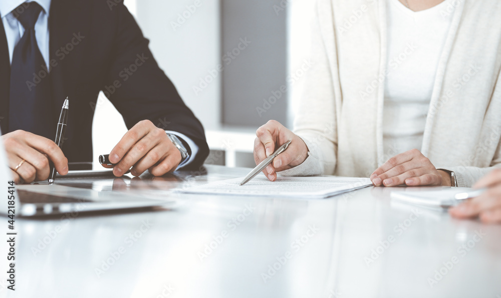 Fototapeta premium Business people discussing contract working together at meeting in modern office. Unknown businessman and woman with colleagues or lawyers at negotiation
