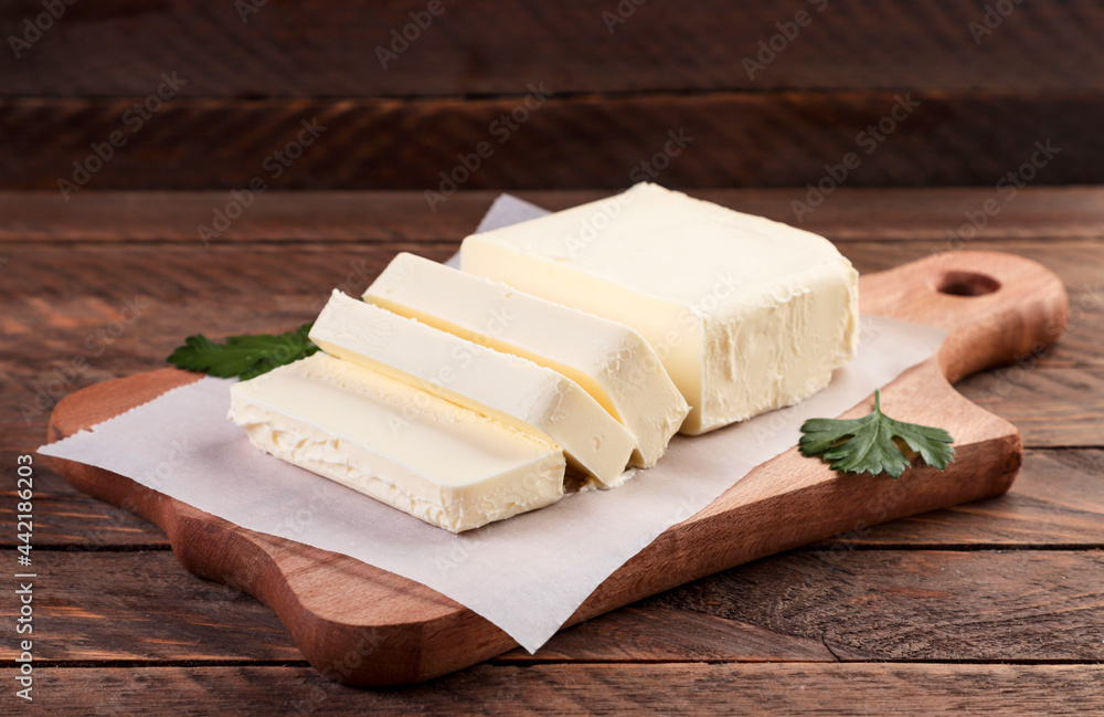 Butter on a kitchen board close-up on a wooden background.