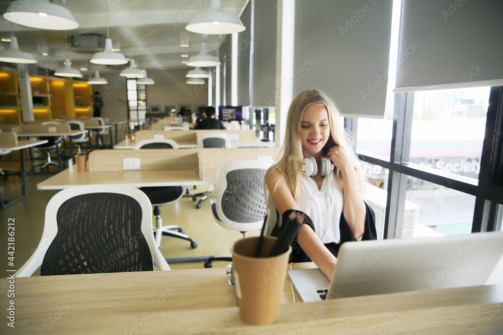 Smiling woman using laptop in work place for small businesses looking to engage audiences and scale content creation can adopt new marketing technology in workspace. Freelancer concept.
