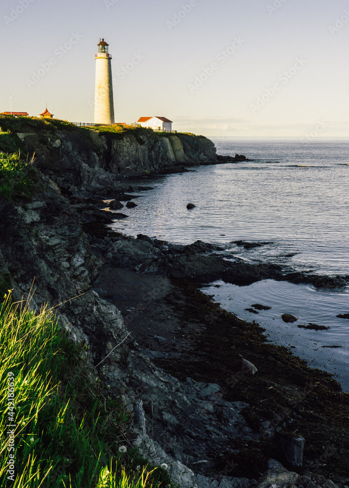 View at sunset on the Atlantic ocean, the cliffs and the Cap Des Rosiers lighthouse, the highest lighthouse in Canada, located near Forillon National Park in Quebec
