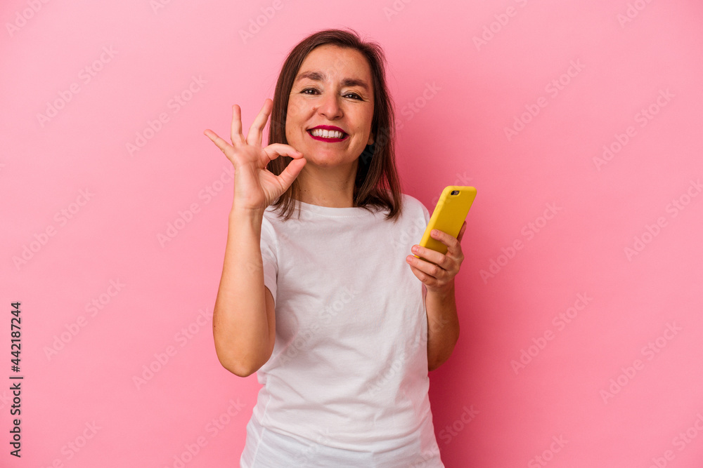 Middle age caucasian woman holding mobile phone isolated on pink background cheerful and confident showing ok gesture. Middle age caucasian woman holding mobile phone isolated on pink background cheerful and confident showing ok gesture.
