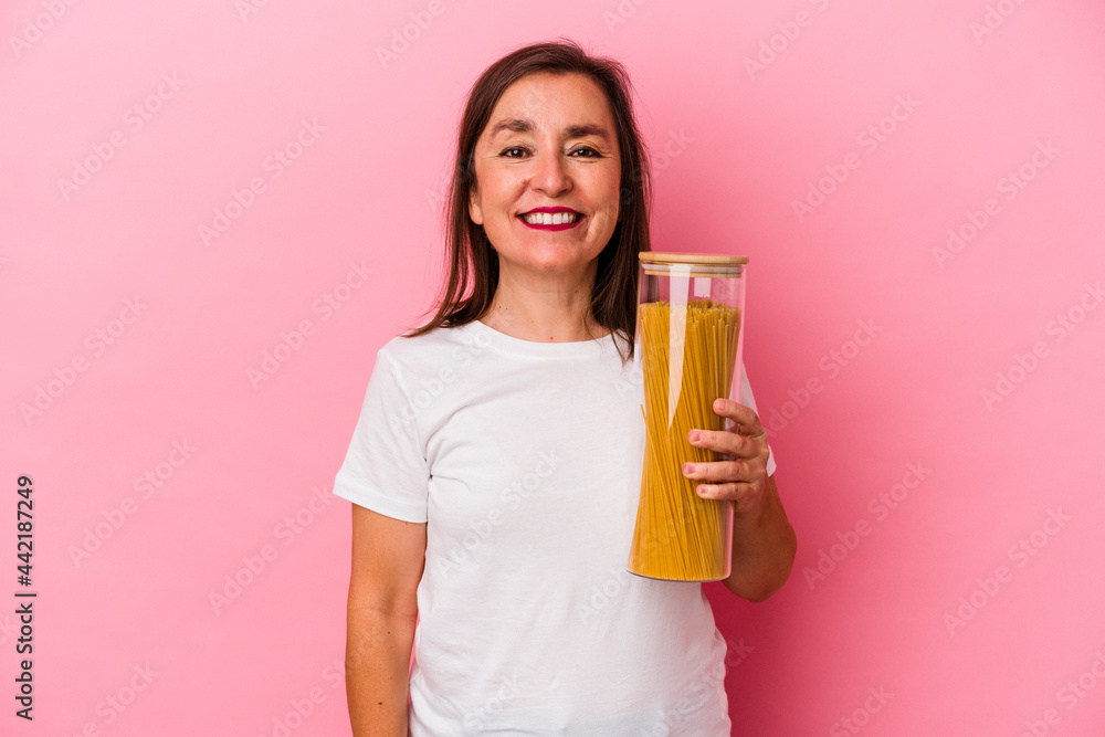 Middle age caucasian woman holding a pasta jar isolated on pink background happy, smiling and cheerful. Middle age caucasian woman holding a pasta jar isolated on pink background happy, smiling and cheerful.
