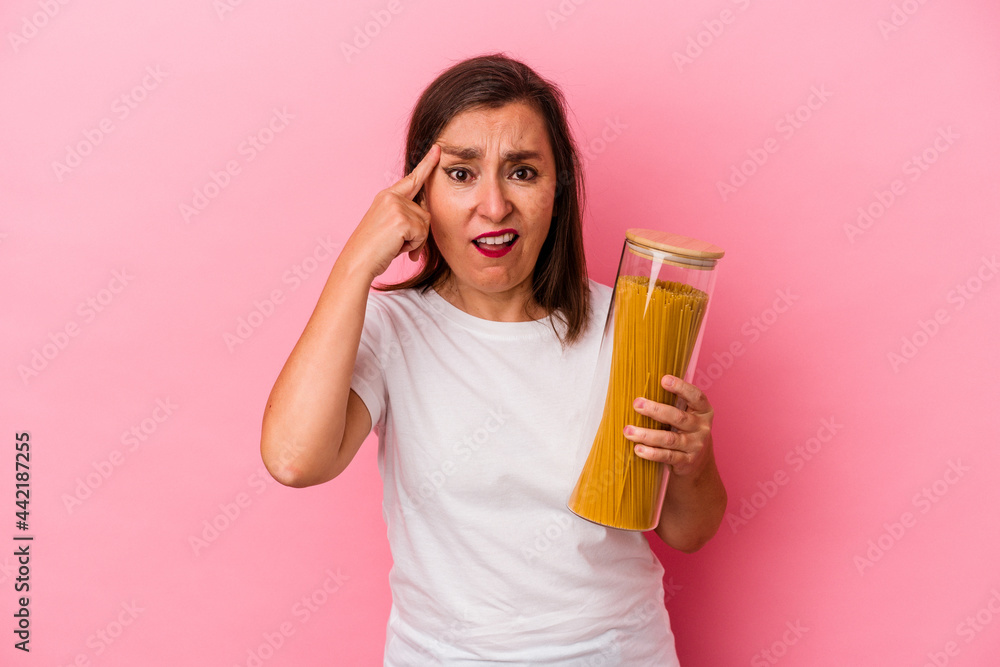 Middle age caucasian woman holding a pasta jar isolated on pink background showing a disappointment gesture with forefinger. Middle age caucasian woman holding a pasta jar isolated on pink background showing a disappointment gesture with forefinger.