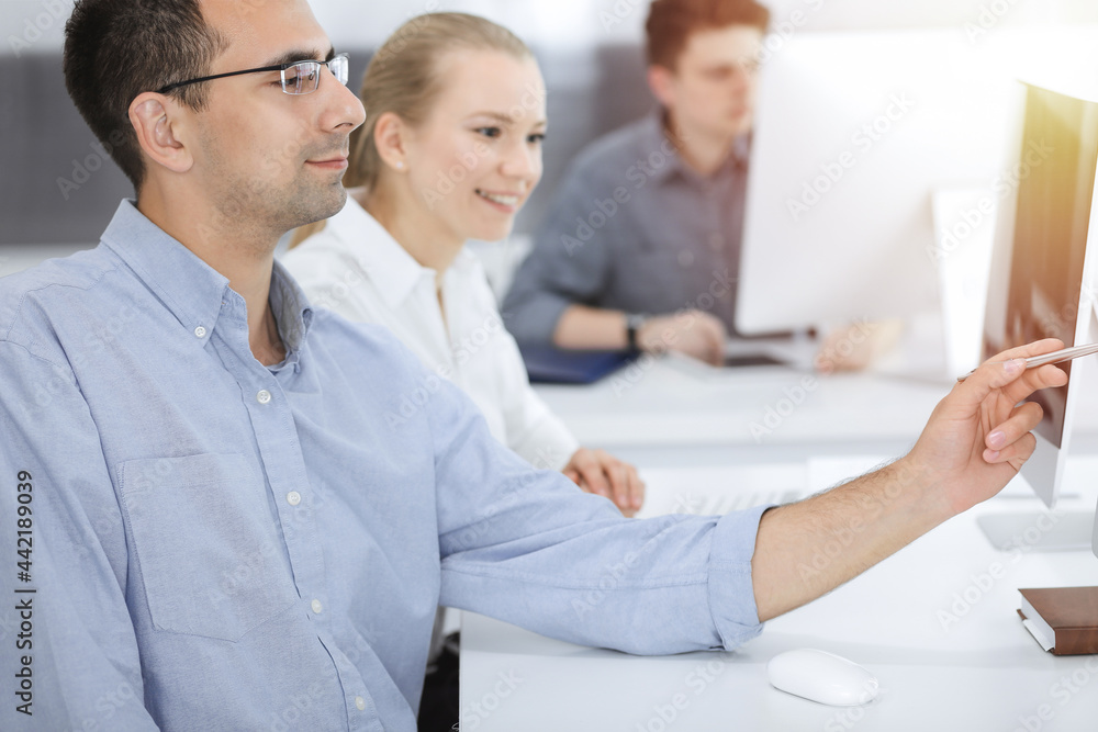 Business people working together in modern office. Happy smiling adult businessman using pc computer with colleagues. Teamwork and partnership concept Business people working together in modern office. Happy smiling adult businessman using pc computer with colleagues. Teamwork and partnership concept