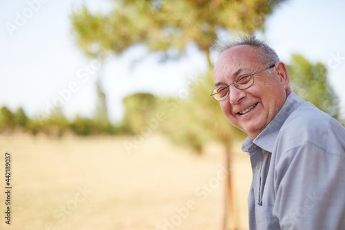 old man smiling with hearing aid and glasses outdoor