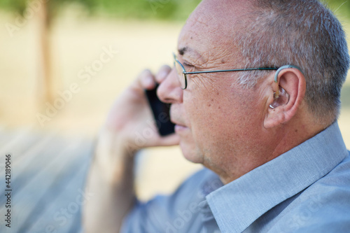 Old man on the phone with hearing aid