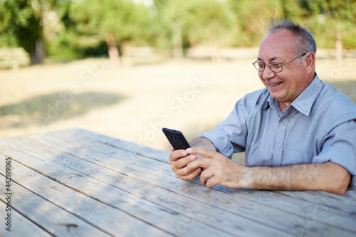 Smiling old man on video call with hearing aid outdoor