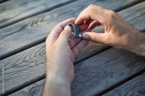 Closeup senior man changing button battery of electronic hearing aid in his hand